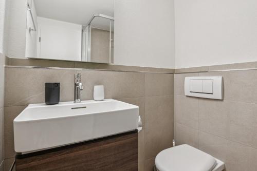 a bathroom with a white sink and a toilet at UP&GREAT Apartments - Chic Urban Homes in Zürich