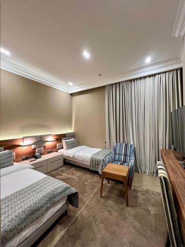 a hotel room with two beds and a chair at Plaza Viktoria Hotel Yerevan in Yerevan