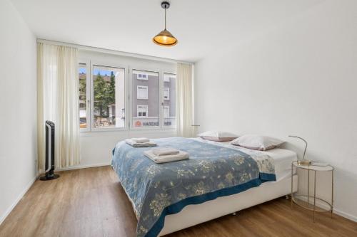 a white bedroom with a bed and a window at UP&GREAT Apartments - Chic Urban Homes in Zürich