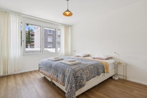 a white bedroom with a bed and a window at UP&GREAT Apartments - Chic Urban Homes in Zürich