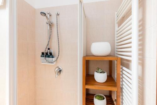 a bathroom with a shower and a shelf with bottles at BGY Airport 10Min Casa Moderna con Ampio Balcone in Bergamo
