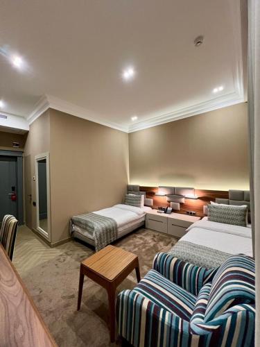a hotel room with two beds and a couch at Plaza Viktoria Hotel Yerevan in Yerevan