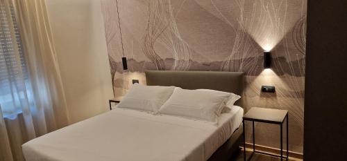 a bed with white sheets and pillows in a room at Hotel La Rocca in San Marino