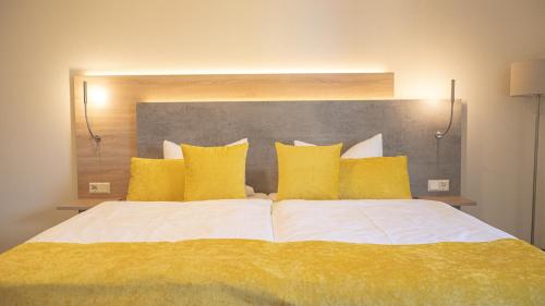a bedroom with a large bed with yellow pillows at Hotel Märkischer Hof in Luckenwalde