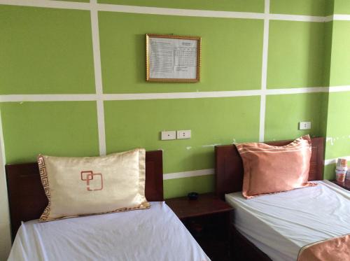 two beds in a room with green walls at Hai Duong Hotel in Hòa Bình