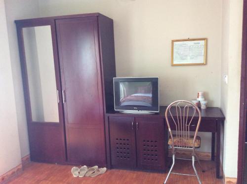 einen Schrank mit einem TV und einem Stuhl in einem Zimmer in der Unterkunft Hai Duong Hotel in Hòa Bình