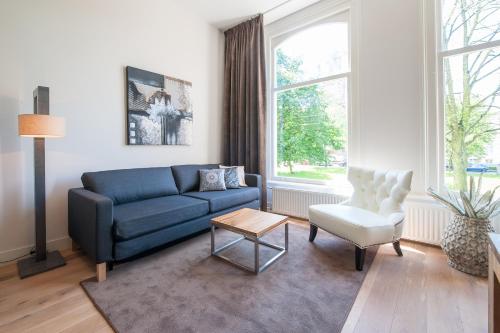 a living room with a blue couch and a chair at Museumpark Apartments in Rotterdam