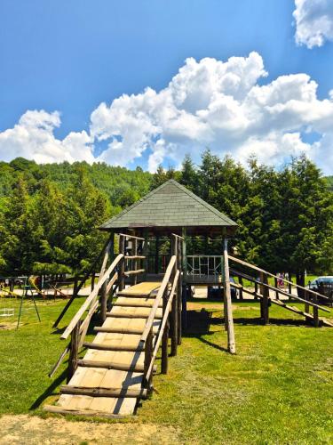 a wooden bridge with a gazebo in a field at Hotel Junior in Kopaonik