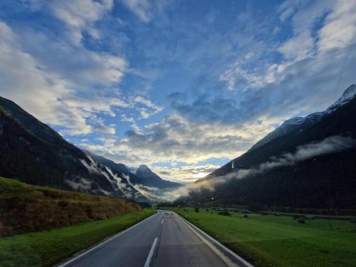 an empty road in the middle of a mountain range at Appartement St. Hubertus in Flirsch