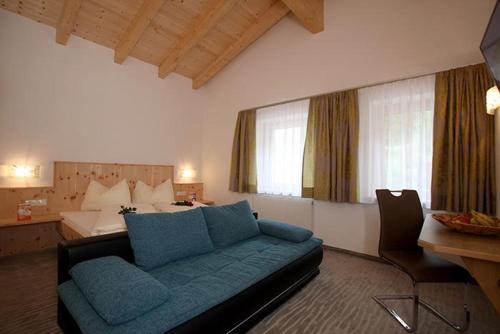 a living room with a blue couch and a bed at Appartement St. Hubertus in Flirsch