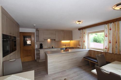 a kitchen with wooden cabinets and a large window at Appartement St. Hubertus in Flirsch
