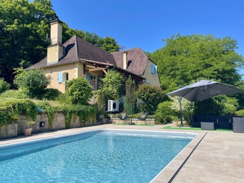 - une piscine avec un parasol en face d'une maison dans l'établissement Propriété aux Eyzies avec piscine privée pour 6 personnes - FR-1-824-12, à Manaurie