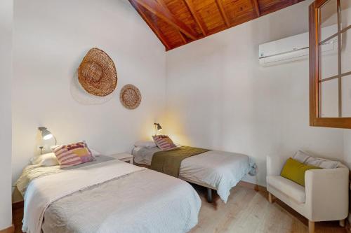 a bedroom with two beds and a chair and a window at Complejo Rural Pajar de Bento in Agulo