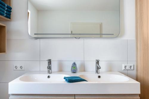 a bathroom with a white sink and a mirror at Ferienwohnung Auf Dem Haldershof in Wangen im Allgäu