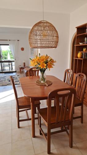 a dining room table and chairs with a vase of flowers at Casa Esperanca in Carvoeiro