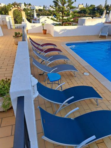 a row of chairs next to a swimming pool at Casa Esperanca in Carvoeiro