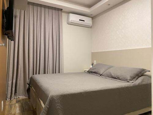 a bedroom with a bed and a window with a air conditioner at Apê coração BC 1 qto 4 pess 300m Praia Garagem Priv in Balneário Camboriú