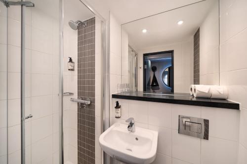 un bagno bianco con lavandino e specchio di Point A Hotel London Westminster a Londra