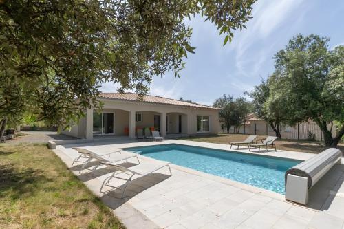 une piscine avec des chaises et une maison dans l'établissement Villa La Barbière, à Sallelles