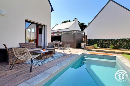 un patio avec une table et des chaises à côté d'une piscine dans l'établissement Ti mod kozh, à Carnac