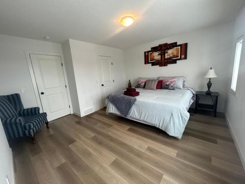 a bedroom with a white bed and a chair at Seton Villas Cozy Four-bed house in Calgary