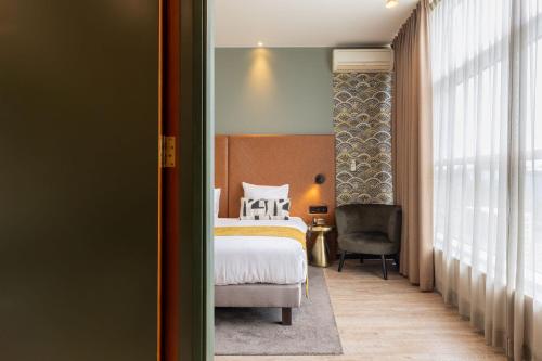 a bedroom with a bed and a desk and a chair at Shanghai Hotel Holland in Delft