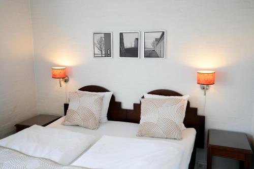 a bedroom with a white bed with three pictures on the wall at Golf Hotel Viborg in Viborg