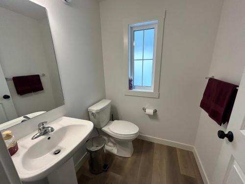 a white bathroom with a toilet and a sink at Seton Villas Cozy Four-bed house in Calgary