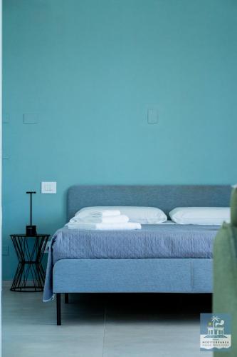 a bed in a room with a blue wall at Villa Mediterranea Apartments - Seaview, Pool & Garden in Bari