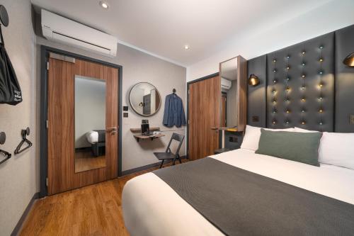 una camera da letto con un letto, una scrivania e uno specchio di Point A Hotel London Westminster a Londra