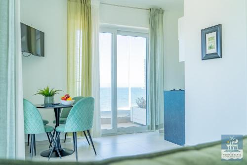 a dining room with a table and chairs and a window at Villa Mediterranea Apartments - Seaview, Pool & Garden in Bari