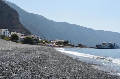 a beach with a cruise ship in the water at Artemisa House in Agia Roumeli