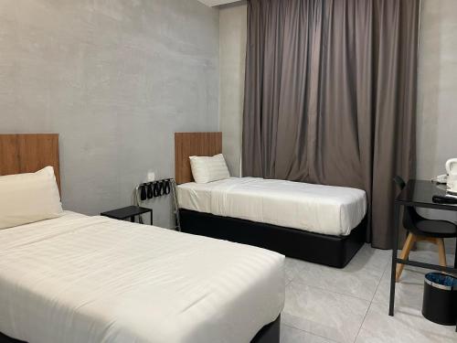 a hotel room with two beds and a desk at HPY Hotel in Ipoh