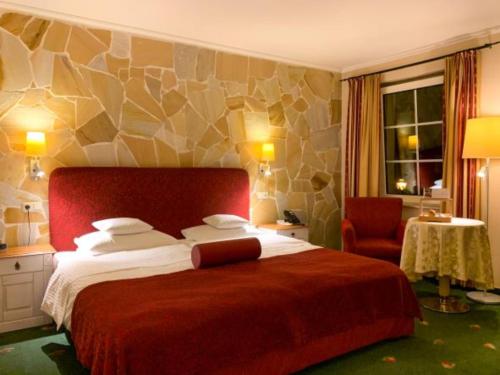 a hotel room with a large bed and a chair at Hotel Zum Stein Wellness & Genuss Resort in Oranienbaum-Wörlitz