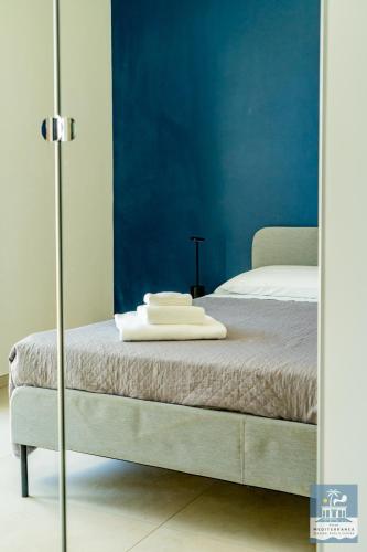 a bedroom with a bed with a blue wall at Villa Mediterranea Apartments - Seaview, Pool & Garden in Bari