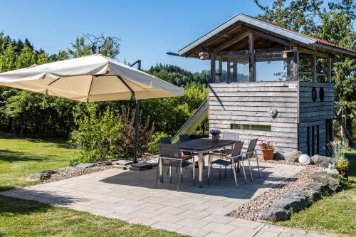 a patio with a table and an umbrella at Ferienwohnung Auf Dem Haldershof in Wangen im Allgäu