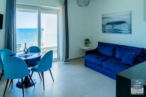 a living room with a blue couch and a table and chairs at Villa Mediterranea Apartments - Seaview, Pool & Garden in Bari