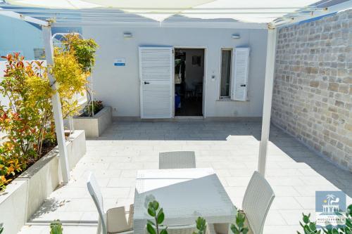 a patio with a table and chairs in front of a building at Villa Mediterranea Apartments - Seaview, Pool & Garden in Bari