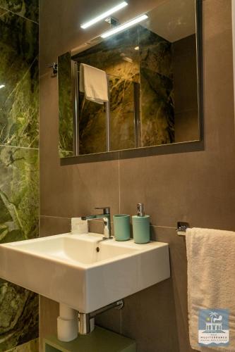 a bathroom with a white sink and a mirror at Villa Mediterranea Apartments - Seaview, Pool & Garden in Bari