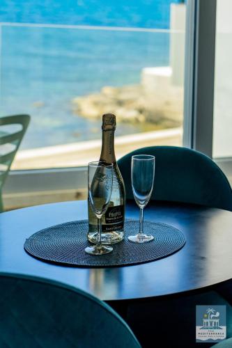 a bottle of wine and two glasses on a table at Villa Mediterranea Apartments - Seaview, Pool & Garden in Bari