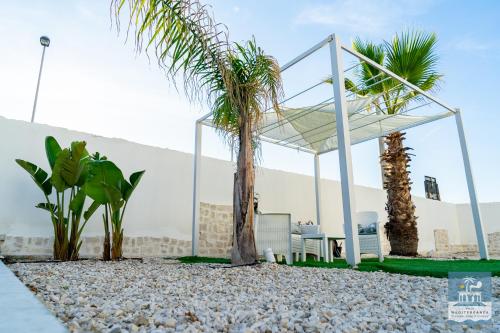 a pavilion with a palm tree and a table and chairs at Villa Mediterranea Apartments - Seaview, Pool & Garden in Bari