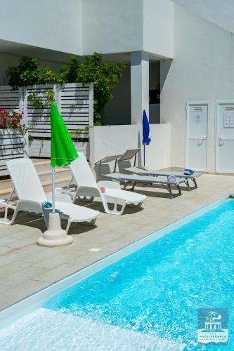 a pool with chairs and umbrellas next to a swimming pool at Villa Mediterranea Apartments - Seaview, Pool & Garden in Bari