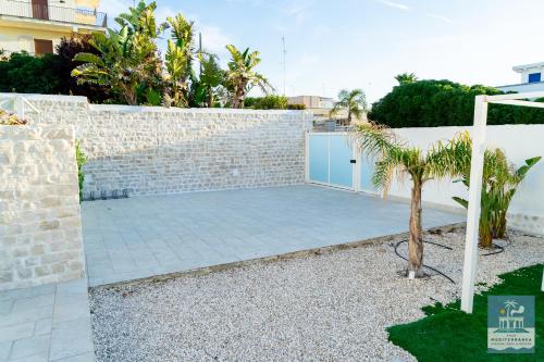 a backyard with a brick wall and a fence at Villa Mediterranea Apartments - Seaview, Pool & Garden in Bari