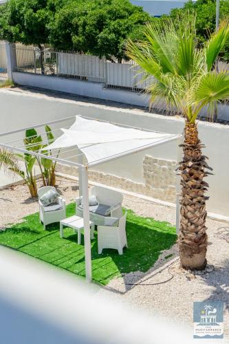 a white umbrella and chairs and a palm tree at Villa Mediterranea Apartments - Seaview, Pool & Garden in Bari
