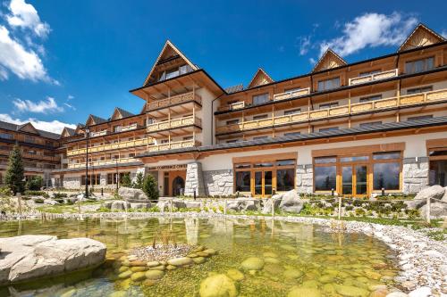 a large building with a pond in front of it at Hotel Bania Thermal & Ski in Białka Tatrzanska