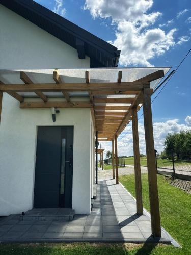 a wooden pergola on the side of a building at Domek Delux -komfortowe apartamenty, domki w Ojcowskim Parku Narodowym Z Jaccuzi in Wola Kalinowska