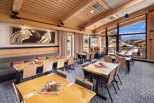 a restaurant with wooden tables and chairs and windows at Hotel Bania Thermal & Ski in Białka Tatrzanska