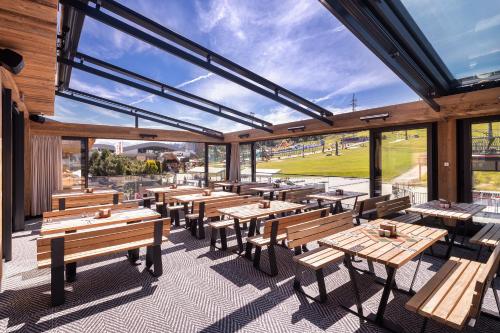 a restaurant with wooden tables and benches and windows at Hotel Bania Thermal & Ski in Białka Tatrzanska