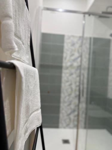 a bathroom with a glass shower with towels on a chair at Casa Teresa Guest Rooms in Parghelia