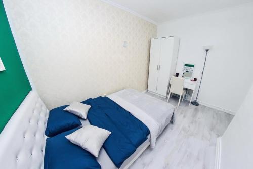 a bedroom with a bed with blue sheets and a desk at Forest Central Sarajevo in Sarajevo